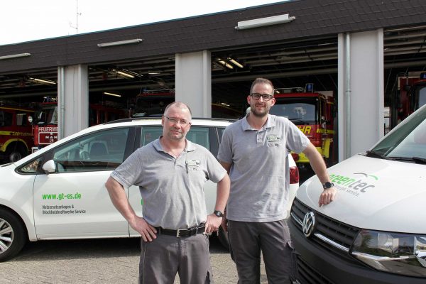 Zwei Monteure vor dem Wartungseinsatz in Ingelheim. Im Hintergrund ist die Fahrzeughalle der Feuerwehr